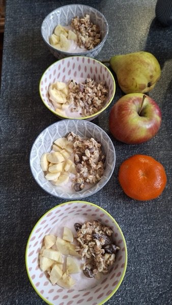 Schüsseln mit Müsli, Apfel, Birne und Mandarine